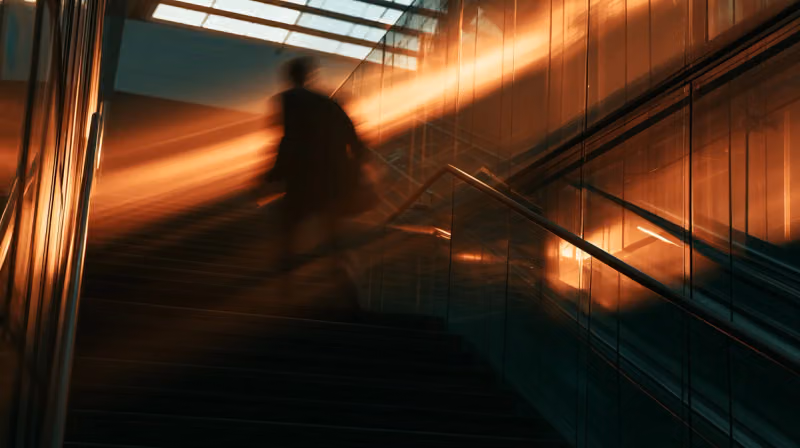 A figure on an escalator inside a glass building